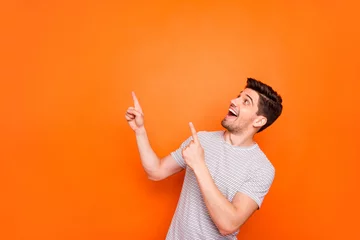Foto op Canvas Photo of attractive funny crazy guy hold hands fingers direct up empty space excited good mood sales person wear striped t-shirt isolated bright orange color background © deagreez