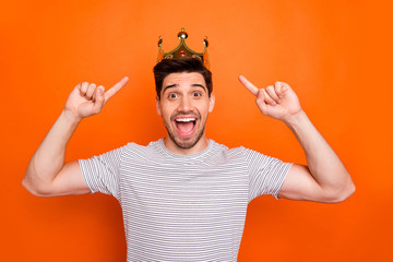 I don't believe. Photo of cool excited guy good mood direct fingers head golden crown amazed prom king open mouth wear striped t-shirt isolated bright orange color background