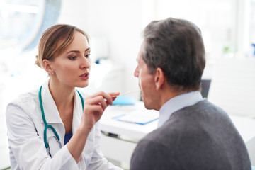 Doctor checking throat of senior man