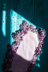 a plaque with lilac on a wooden turquoise background with natural light.