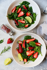 Fitness food spinach and strawberry salad in white bowls on a light table. food delivery of diet dishes. dish for spring and summer menu business lunch. the view from the top. selective focus