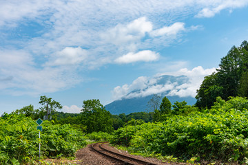 Hakodate main line railroad at Town Niseko in springtime sunny day with Mount Yotei in the background. Shiribeshi Subprefecture, Hokkaido, Japan