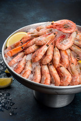 A lot of shrimp with lemon in an iron dish