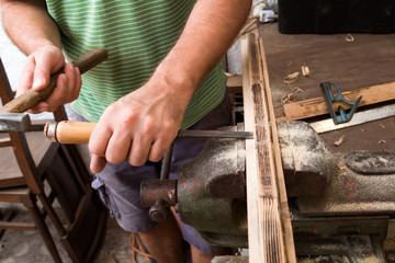 Male carpenter working on old wood in a retro vintage workshop.