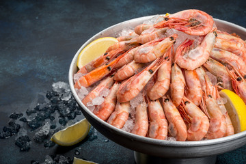 A lot of shrimp with lemon in an iron dish