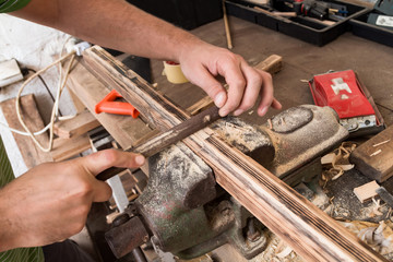 Male carpenter working on old wood in a retro vintage workshop.