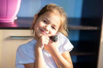 Little girl cuddles with her pet - Mongolian gerbil and smiles
