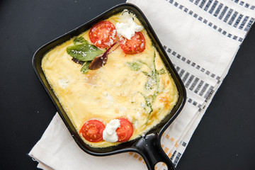 Omelette with vegetables cherry tomatoes and cheese. Italian healthy breakfast. Frittata. Scrambled eggs. Cooking omelet in a pan, ready to eat