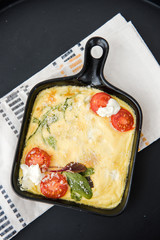 Omelette with vegetables cherry tomatoes and cheese. Italian healthy breakfast. Frittata. Scrambled eggs. Cooking omelet in a pan, ready to eat