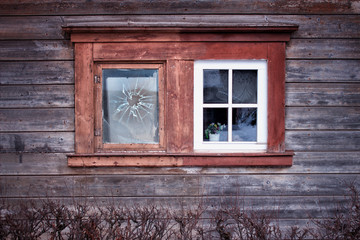 Fototapeta na wymiar The old one vs new one.Two old windows in the wall of ancient Latvian wooden house.