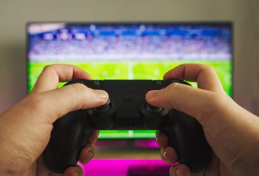 Stock photo of some hands with a gamepad playing a soccer game
