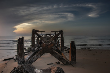 Looking out at Broken old structure remains of pier  in the during beautiful twilight in the sea.