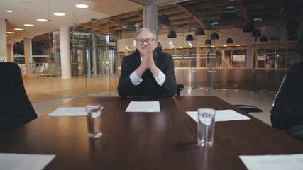 Mature businessman rubbing hand together in office