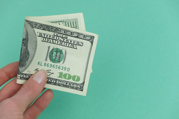 Girl holds money, American banknote on green background. Concept of money, earning, taxes, paying twice.