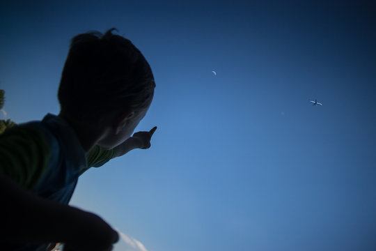 Low Angle View Of Boy Pointing At Clear Blue Sky