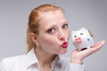Fototapeta na wymiar young woman gives her piggy bank a kiss
