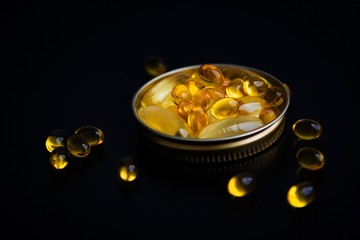 Capsules of fish oil in gold cup on black