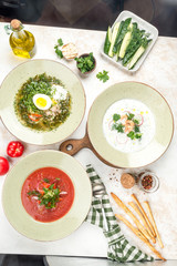 On the photo there are three dishes of borsch, okroshka, soup with egg