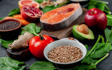 Selection of healthy food: salmon, fruits, seeds, cereals, superfoods, vegetables, leafy vegetables on a stone background. Healthy food for people.