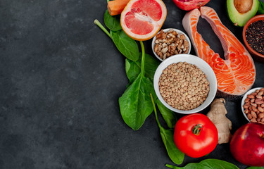 Fototapeta na wymiar Selection of healthy food: salmon, fruits, seeds, cereals, superfoods, vegetables, leafy vegetables on a stone background with copy space for your text. Healthy food for people.
