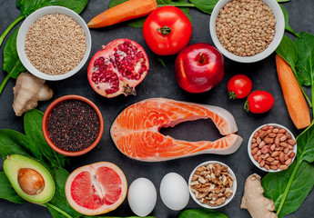 Selection of healthy food: salmon, fruits, seeds, cereals, superfoods, vegetables, leafy vegetables on a stone background. Healthy food for people.