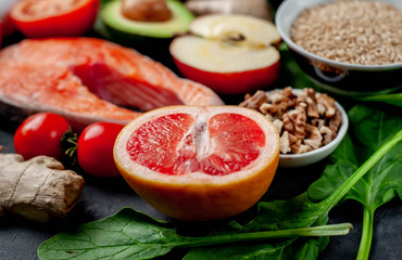 Selection of healthy food: salmon, fruits, seeds, cereals, superfoods, vegetables, leafy vegetables on a stone background. Healthy food for people.