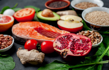 Selection of healthy food: salmon, fruits, seeds, cereals, superfoods, vegetables, leafy vegetables on a stone background. Healthy food for people.