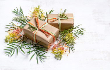Gifts/presents surrounded by Australian native Grevillea foliage on a rustic white wooden...