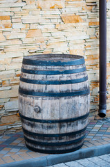 Old wooden barrel with black iron rings left on the stone street. Old fashioned antique whiskey wood barrel or wine cask.