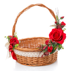 Fototapeta na wymiar Decorated natural vine basket with high handle. Decor of red roses and lace ribbon on white background