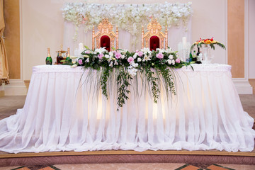 The Presidium of the newlyweds at the wedding, a table for the bride and groom. Banquet decor. Wedding presidium in restaurant. Banquet table for newlyweds. Luxury wedding decor