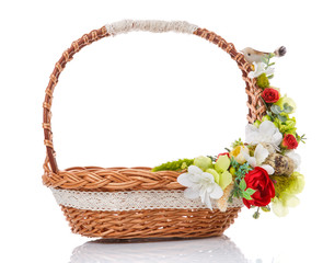 Fototapeta na wymiar Brown wicker basket with original handle. Decor with flowers, eggs and a small ceramic bird. Made in a rustic style. Isolated on a white background