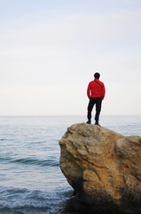 Man in the wild sea view background.A man stands on a rock on the background of the sea.