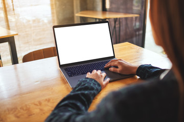 Mockup image of a woman using and typing on laptop computer with blank white desktop screen on wooden table