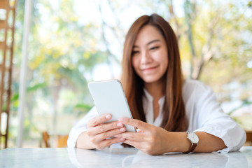 Closeup image of a beautiful asian woman holding and using mobile phone