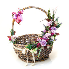 Fototapeta na wymiar Decorated Easter basket with high handle. Decor of quail eggs and various flowers on white background