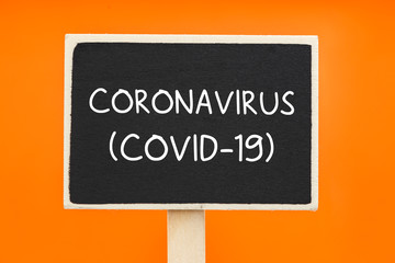 Coronavirus written on a chalkboard against orange background - health Concept