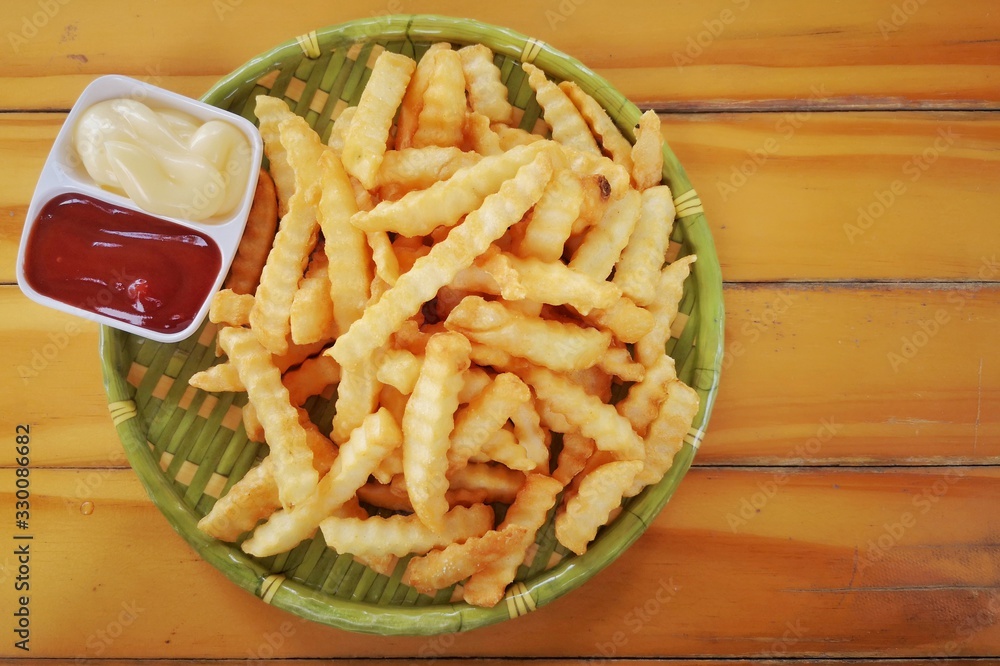 Wall mural french fries, potato chips, placed in a container made from green bamboo there is a cup with red ket