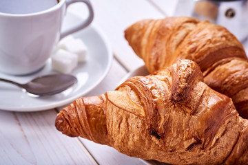 Continental or French breakfast. Croissants and cup of black coffee with sugar and spoon.