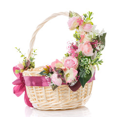 Wicker basket with delicate pastel decor. Pink flowers and ribbon with bow. Isolated on a white background