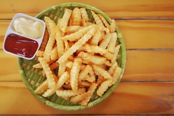 French fries, Potato chips, placed in a container made from green bamboo There is a cup with red ketchup and white mayonnaise, wooden flooring as the background.