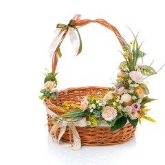 Fototapeta na wymiar Composition of flowers and green leaves in light colors decorates a wicker basket. Isolated on a white background