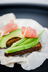 Avocado sandwich with jamon. Toasted bread for healthy breakfast or snack, copy space. Spanish tapas. Italian brushetta. Vegan avocado sandwich top view close-up