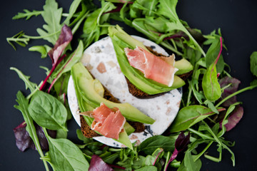 Avocado sandwich with jamon. Toasted bread for healthy breakfast or snack, copy space. Spanish tapas. Italian brushetta. Vegan avocado sandwich top view close-up