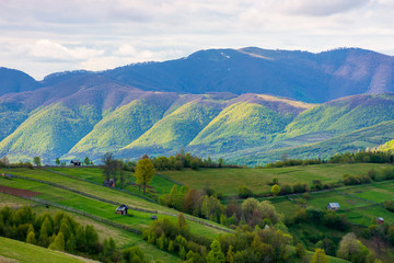 rural landscape in mountains. dappeled light on forested hills. wooden fence along the hillside. beautiful nature scenery in spring. wonderful weather with clouds