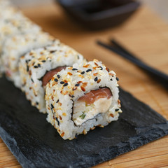 Sushi roll with salmon, eel, cucumber, cream cheese and sesame on a black board. Japanese food.