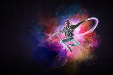 Modern female dancer jumping in hoodie with colourful splashes background. Mixed media