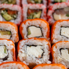 Closeup of sushi roll with salmon, avocado and cheese. Japanese cuisine restaurant. Background with sushi