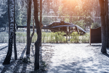 Black private modern luxury helicopter standing on grass field near forest at country rural landscape. Rich buiness lifestyle travel. VIP aero taxi service .Early morning departure