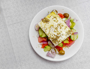 original feta cheese in Greek salad plate, top view close up